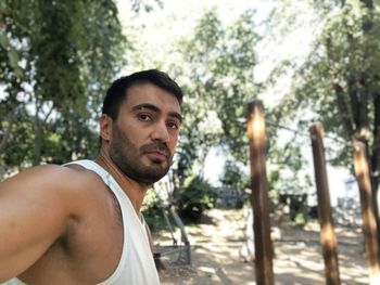 Portrait of young man standing against trees