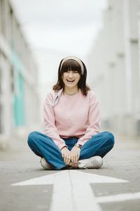 Portrait of smiling young woman sitting on street