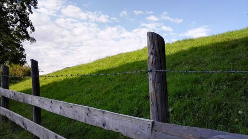 Wooden fence on field against sky