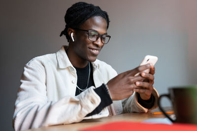 Happy black guy freelancer reading text message on smartphone while working remotely from home