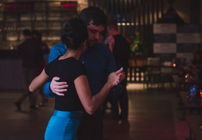 Rear view of couple standing in illuminated city at night