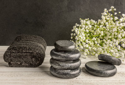 Massage basalt stones for spa and a towel and white blossoms on dark background.