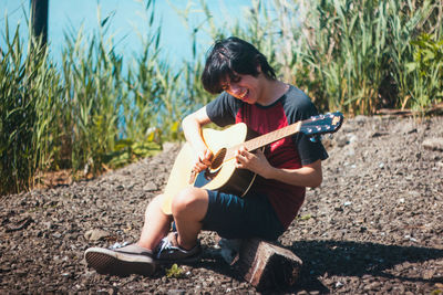 Young woman playing guitar on field