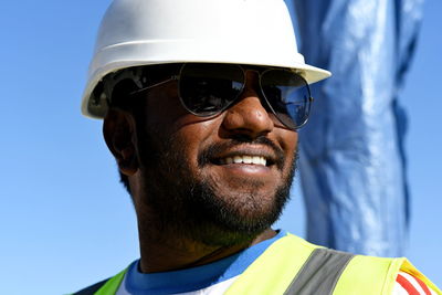 Close-up of smiling young man wearing sunglasses standing against sky