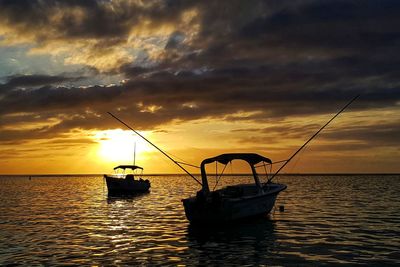 Fishing boat on sea against sky during sunset