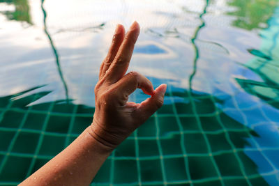 Midsection of person hand on swimming pool