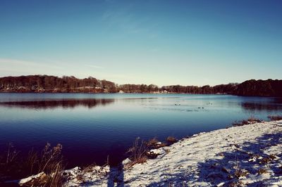 Scenic view of lake against clear blue sky