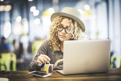 Woman using phone while sitting on table