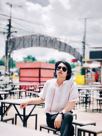 Portrait of woman wearing sunglasses while sitting at outdoor cafe