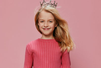 Portrait of young woman standing against pink background