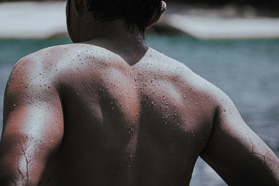 Midsection of shirtless man in swimming pool