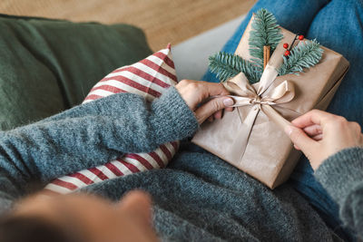 Unrecognizable woman unpacks a beautiful wrapped christmas present.