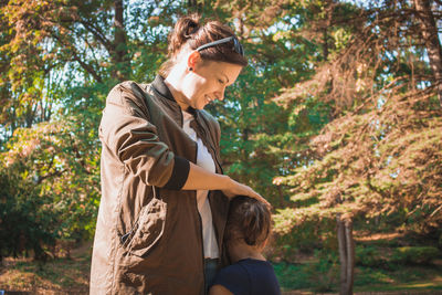 Side view of girl embracing smiling mother in park during autumn