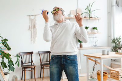 Rear view of woman using mobile phone while sitting at home