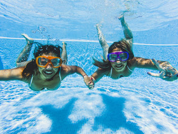 Portrait of happy female friends swimming in pool