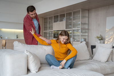 Full length of young woman sitting on bed at home