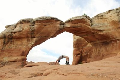 Man bending over backwards against rock formations