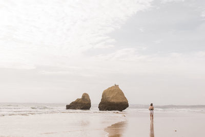 Woman walking at beach against sky