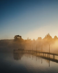 Pier over lake against sky during sunrise