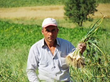 Portrait of mature farmer holding vegetables