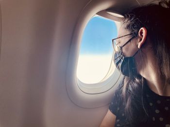 Portrait of young woman looking through airplane window