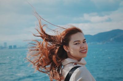 Portrait of happy woman against sea against sky