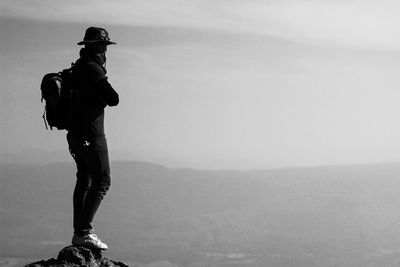 Rear view of man standing on landscape against sky