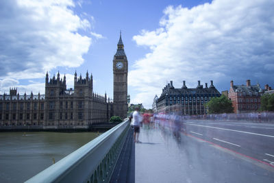 Blurred motion of people on westminster bridge against cloudy sky