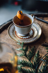 Hot toddy tea cup on whiskey barrel with greenery and wreath making supplies