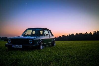 Vintage car on field during sunset