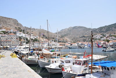 Sailboats moored at harbor against clear sky