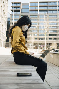 Profile of woman with face mask sitting outside working