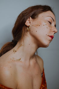 Close-up of woman with dried flowers on face and neck