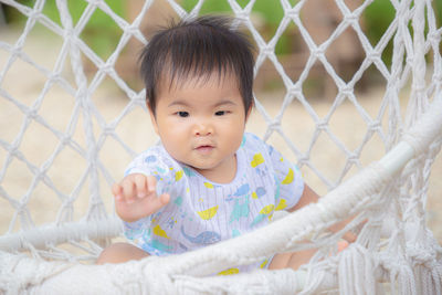 Portrait of cute baby girl seen through chainlink fence