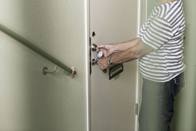 Midsection of senior woman locking apartment door