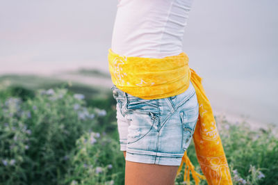 Low section of woman standing against yellow background