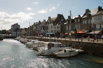 Sailboats moored in port by city buildings