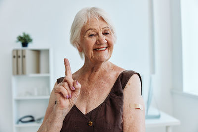 Smiling senior woman gesturing at hospital