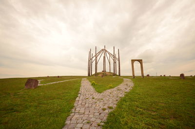 Traditional windmill on landscape against cloudy sky