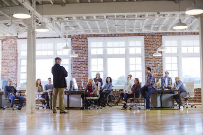 Businessman talking with colleagues sitting at desks in office