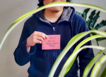 Midsection of man holding handwritten card stating men have feelings too