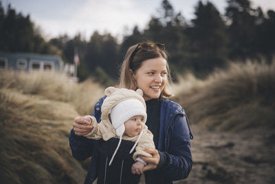 A woman with an infant is standing on the californian beach