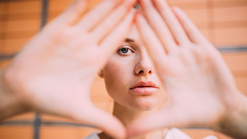 Portrait of young woman gesturing over face