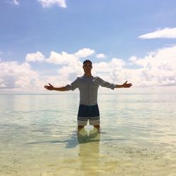 Portrait of young man with arms outstretched standing in sea