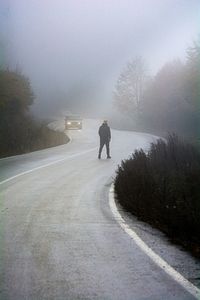 Rear view of man walking on road in winter