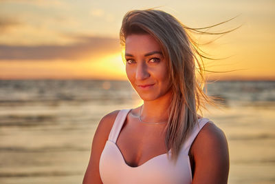 Portrait of beautiful woman on beach against sky during sunset