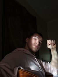 Portrait of young man in dark at home