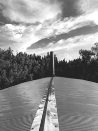 Boardwalk amidst trees against sky
