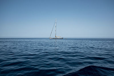 Sailboat sailing on sea against clear sky