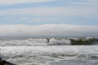 Man surfing in sea against sky